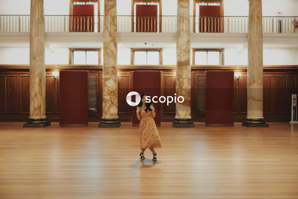 Woman in long orange dress standing in big hall