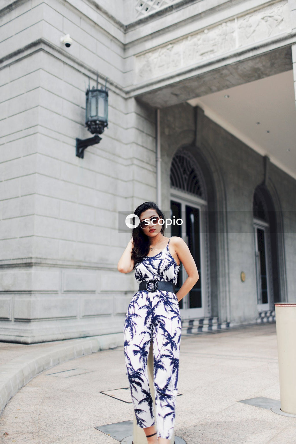 Woman in light and dark jumpsuit posing in front of building