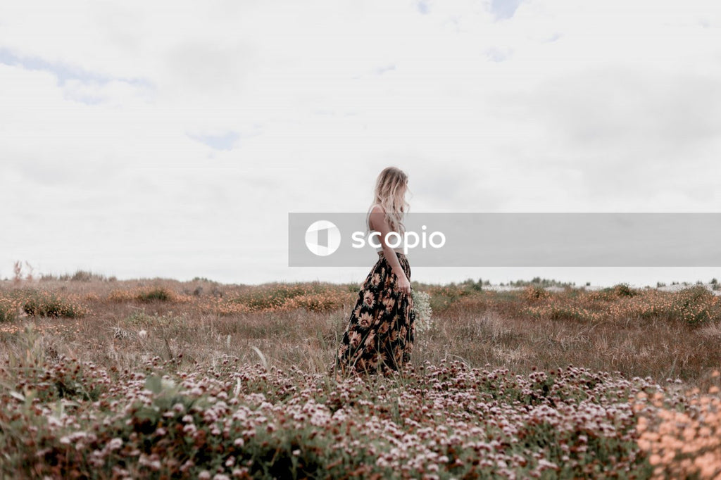 Woman in black and white floral dress standing on flower field