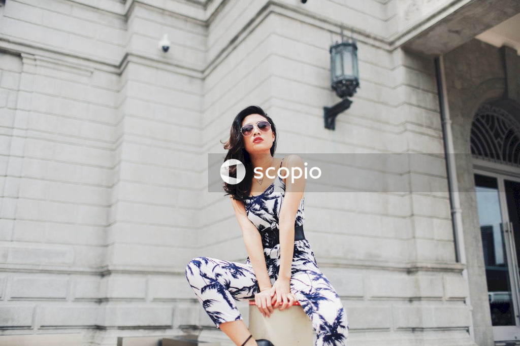 Woman in light and dark jumpsuit posing in front of building