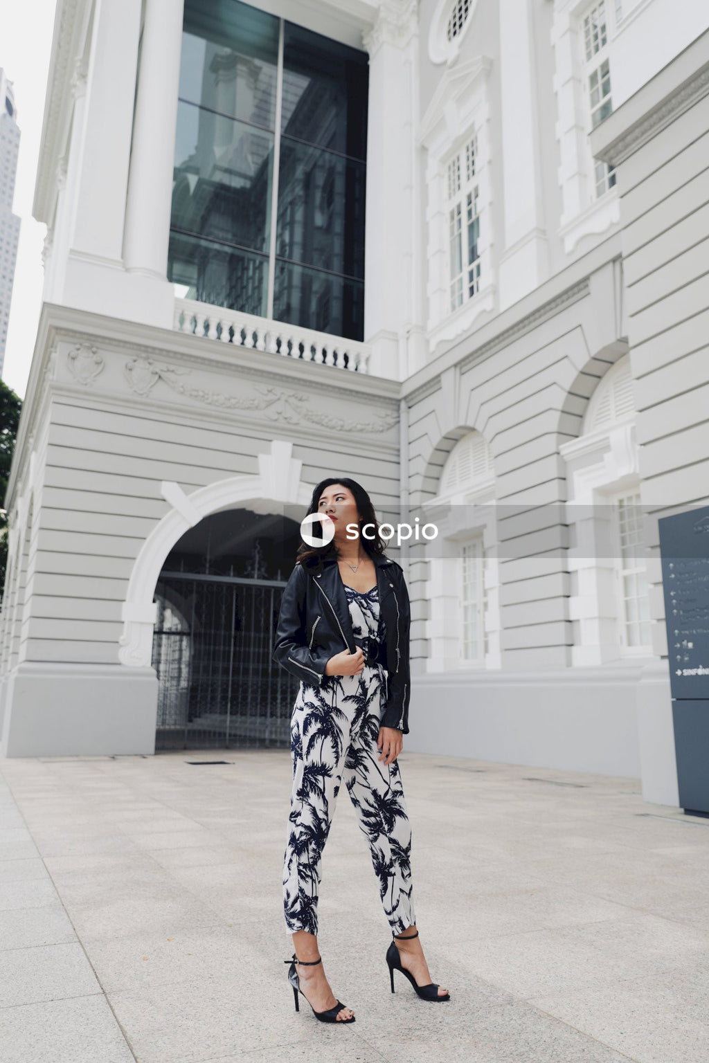 Woman strikes a pose on white floor tiles, wearing a black and white floral long sleeve dress