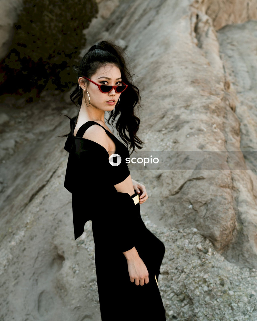 Woman in dark outfit posing on rock