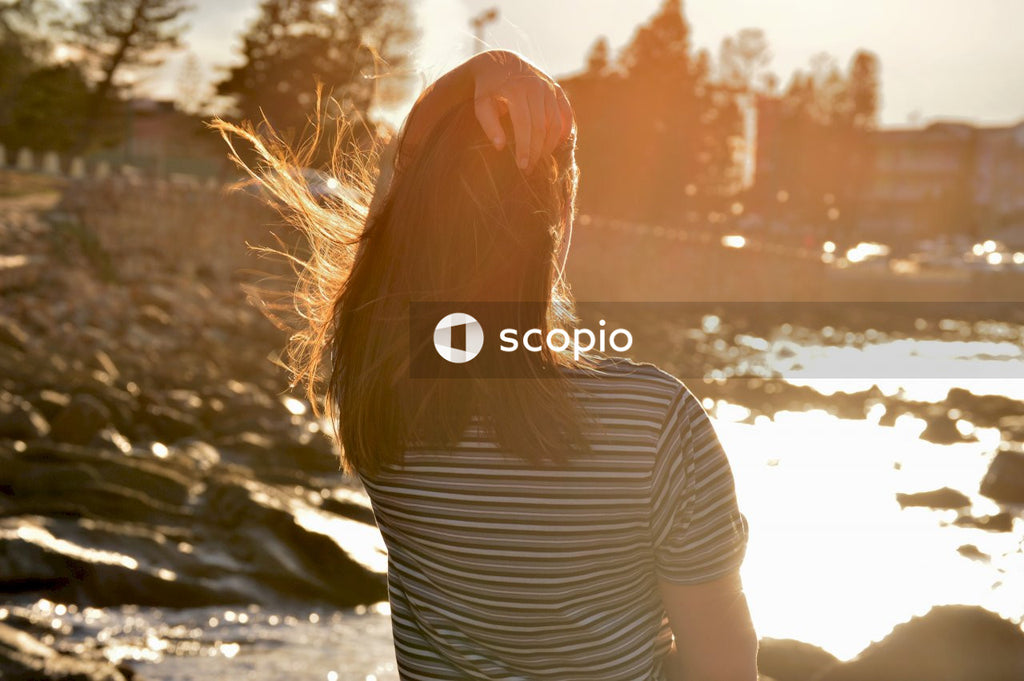 Woman in white and black striped shirt standing near body of water