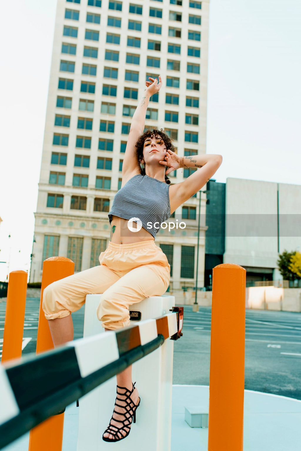 Woman in black and white polka dot tank top and beige pants sitting on bench