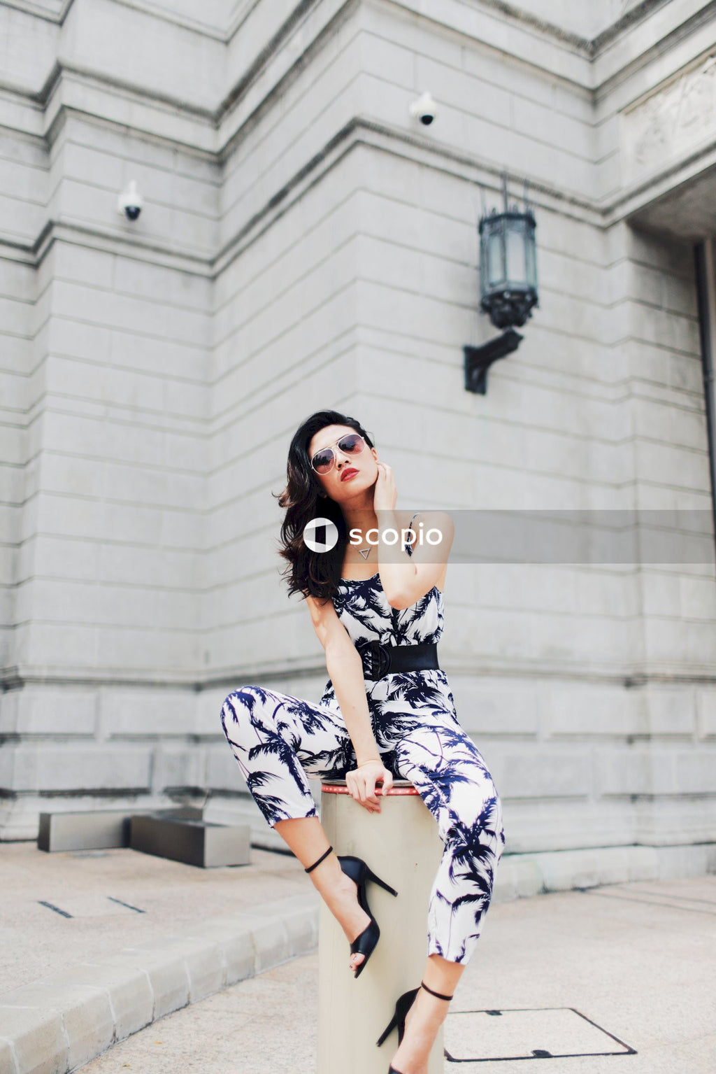 Woman in light and dark jumpsuit posing in front of building