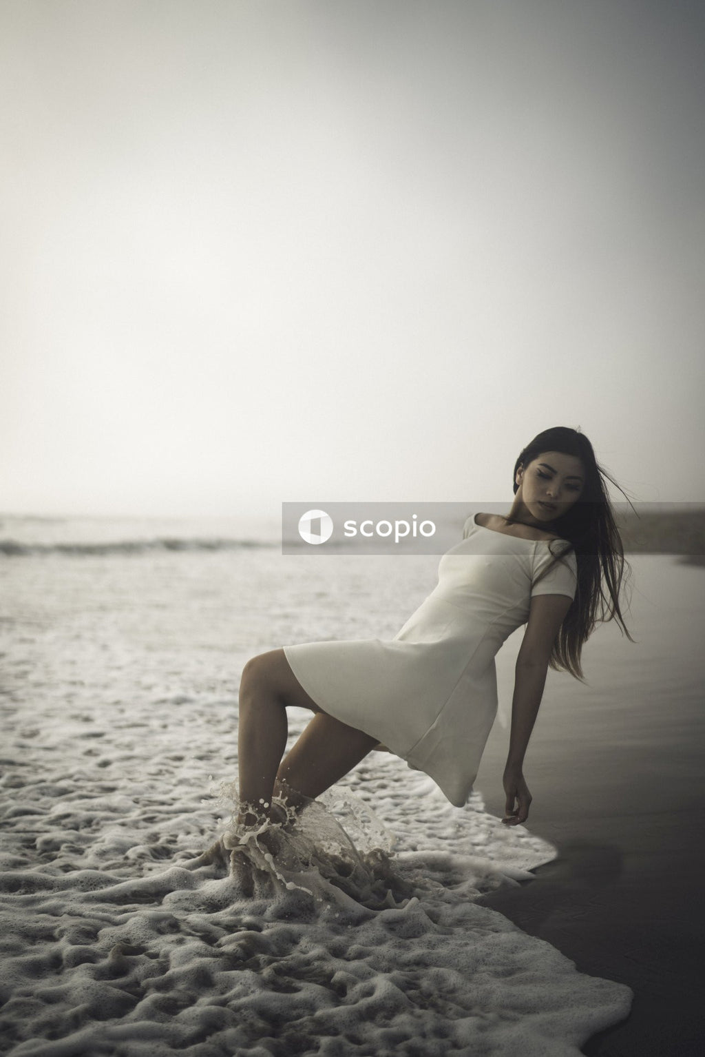 Woman in short light dress standing on sandy shore