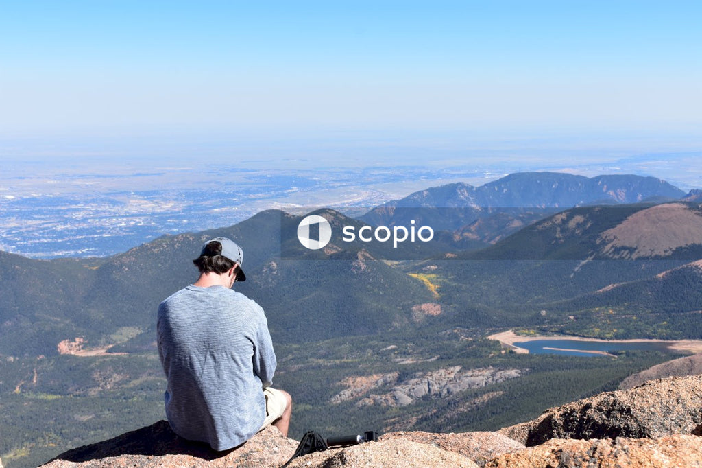 Man in gray t-shirt sitting on rock mountain
