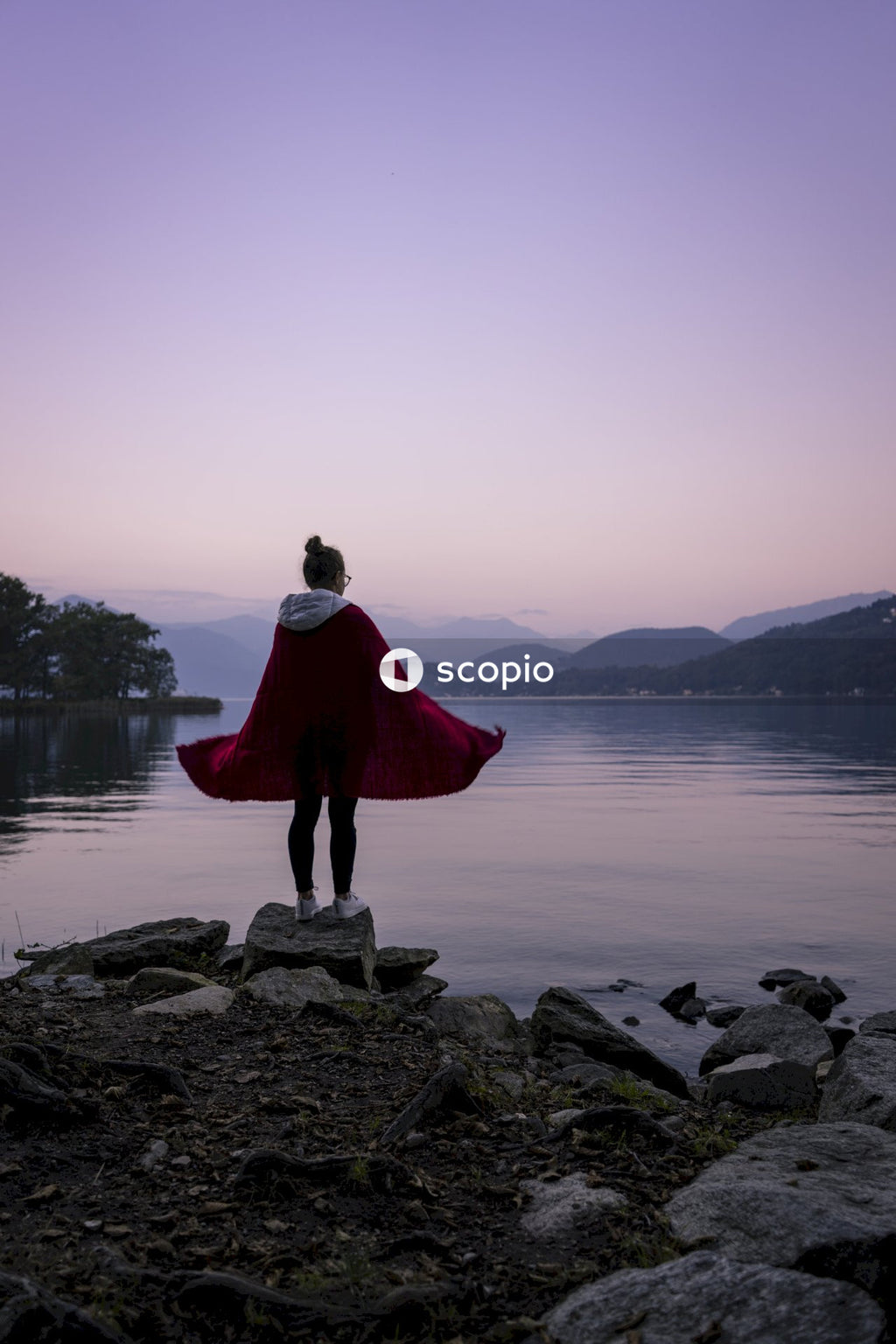 Woman in red dress standing on rocky shore