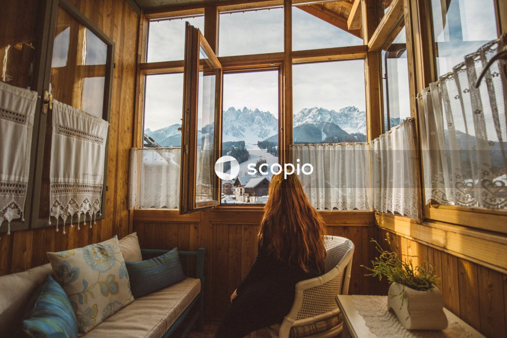 Woman sitting on  armchair looking at mountains through the window