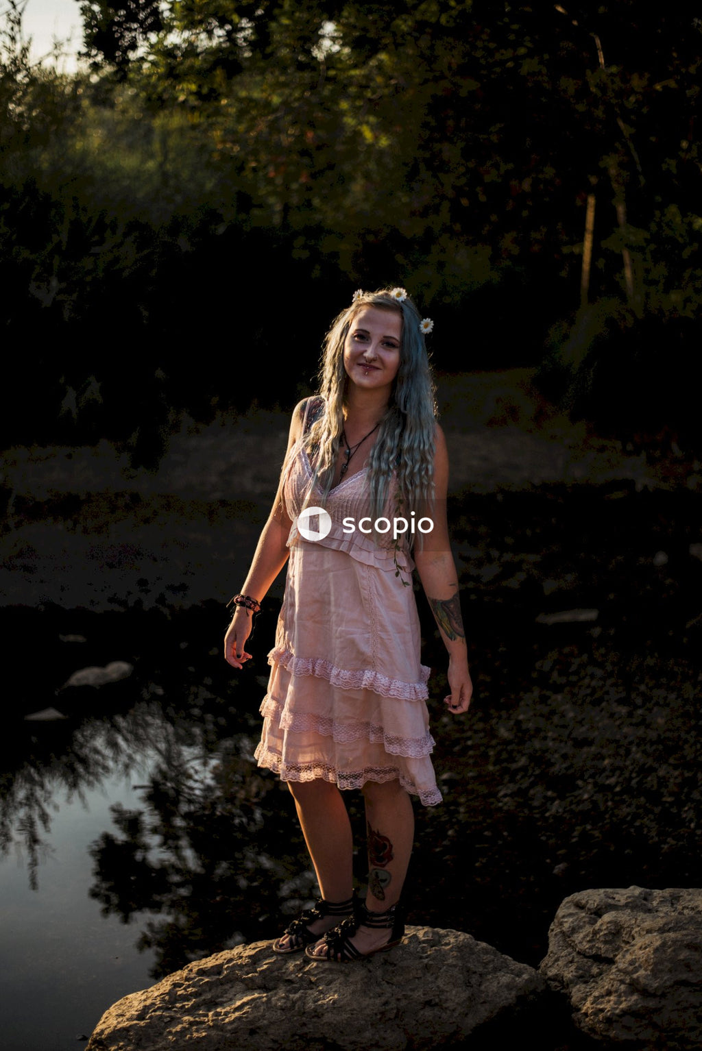 Woman in white and red dress standing on brown soil near river