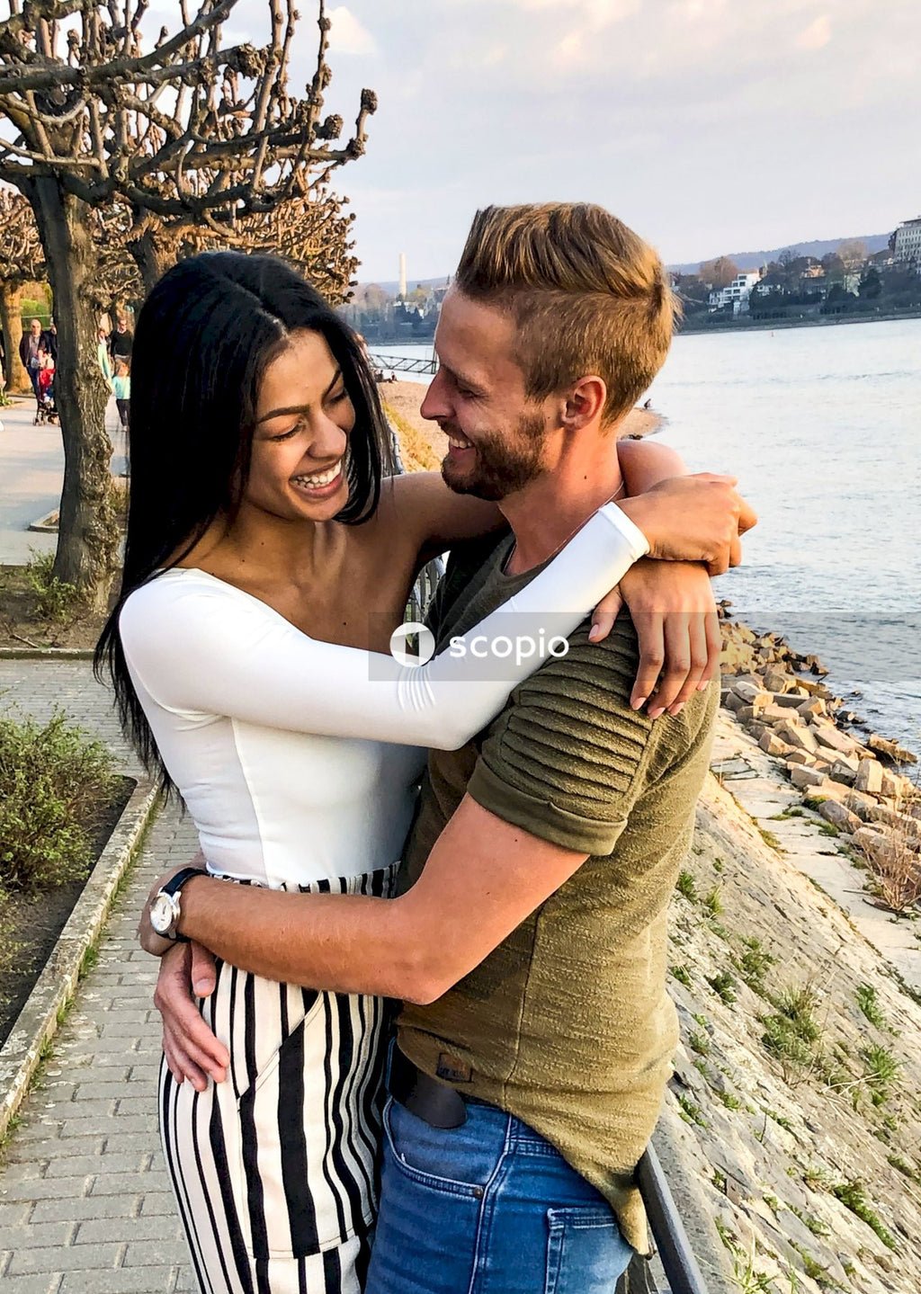 Man and woman kissing near body of water