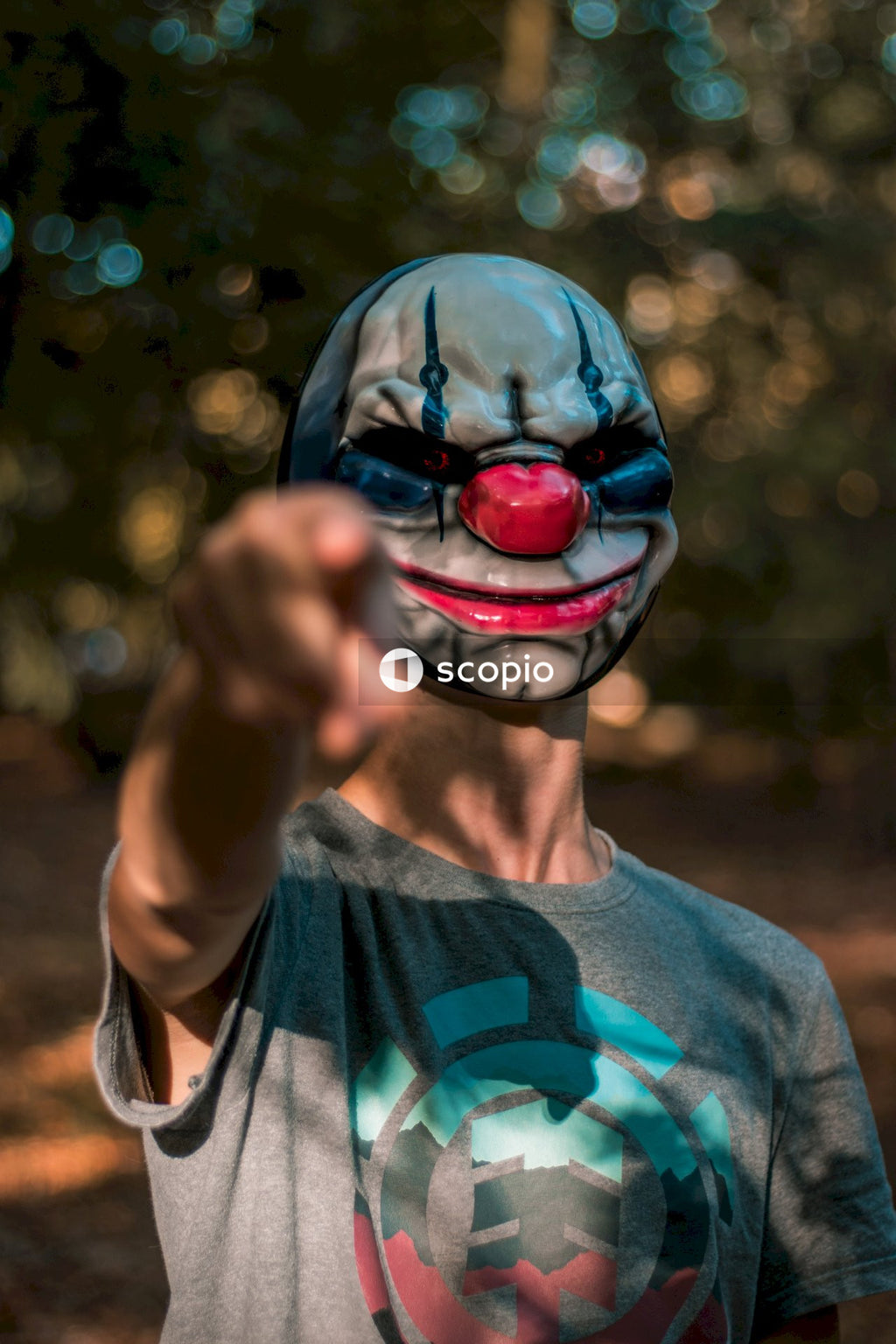 Man wearing black and red mask pointing index finger