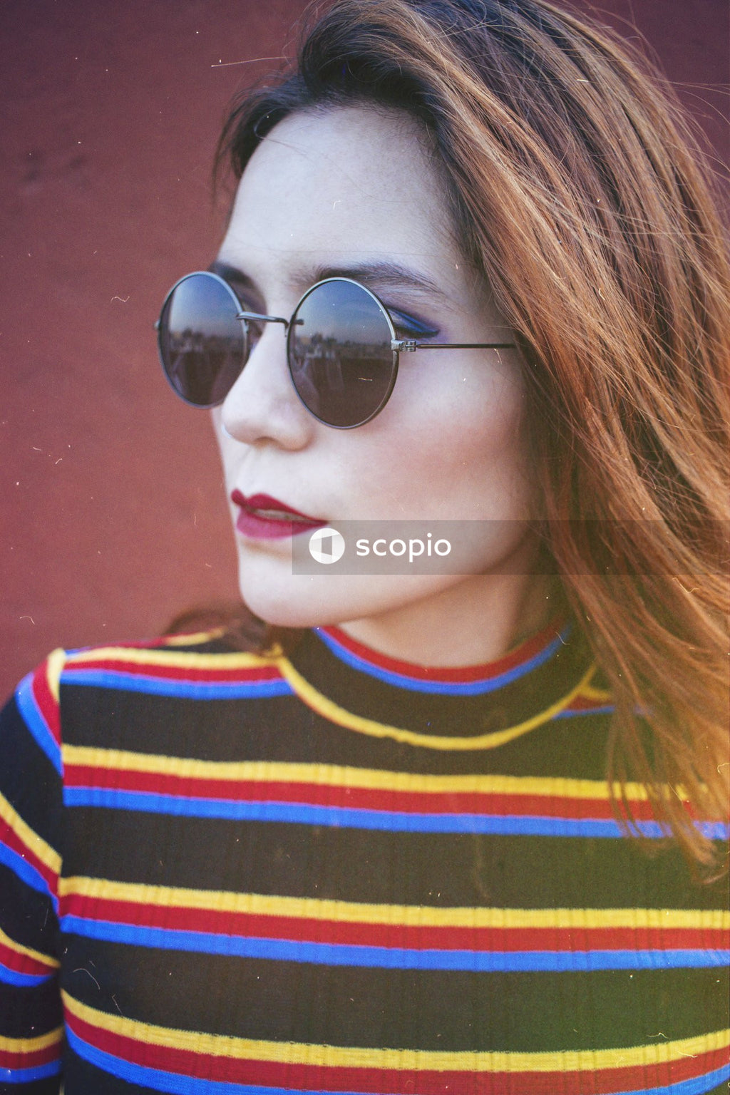Portrait of young woman in colorful striped shirt wearing sunglasses