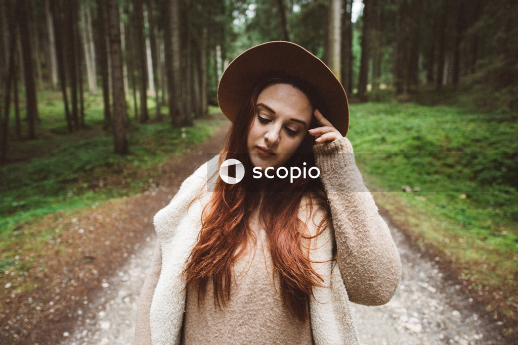 Portrait of mature woman with brown hat standing in the woods