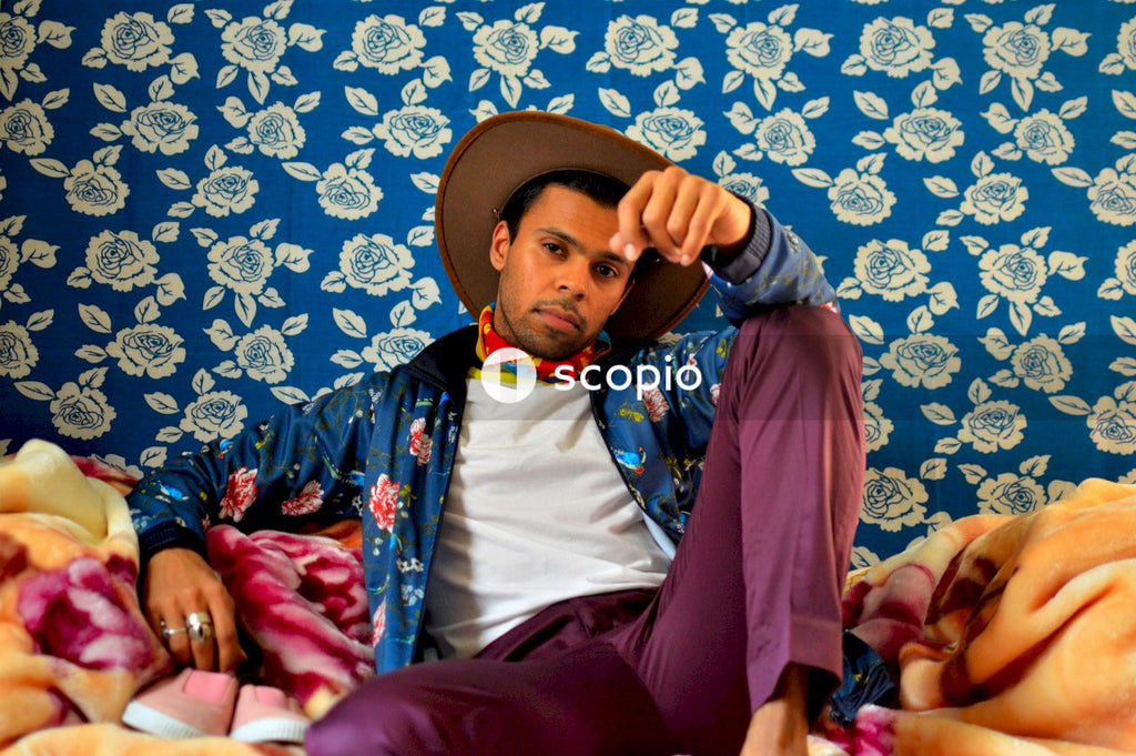 Man in white shirt and blue pants wearing brown hat sitting on blue and white floral