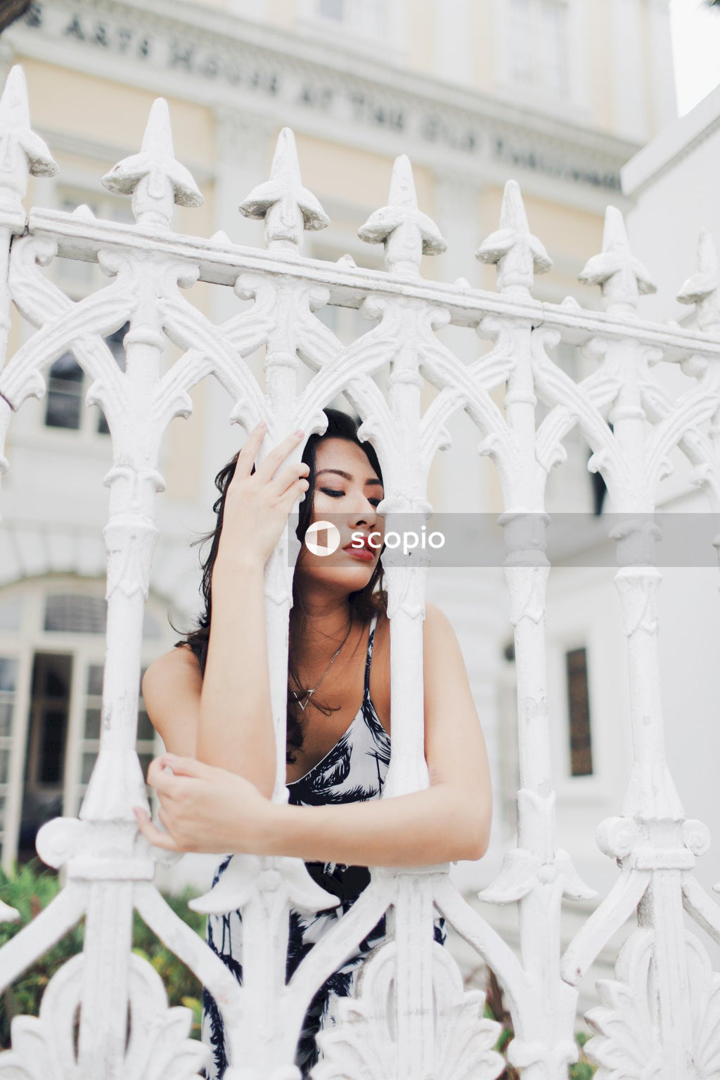 Woman in light and dark jumpsuit behind light building fence
