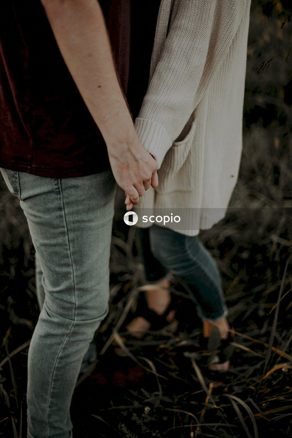 Man and woman holding hands and standing on green field