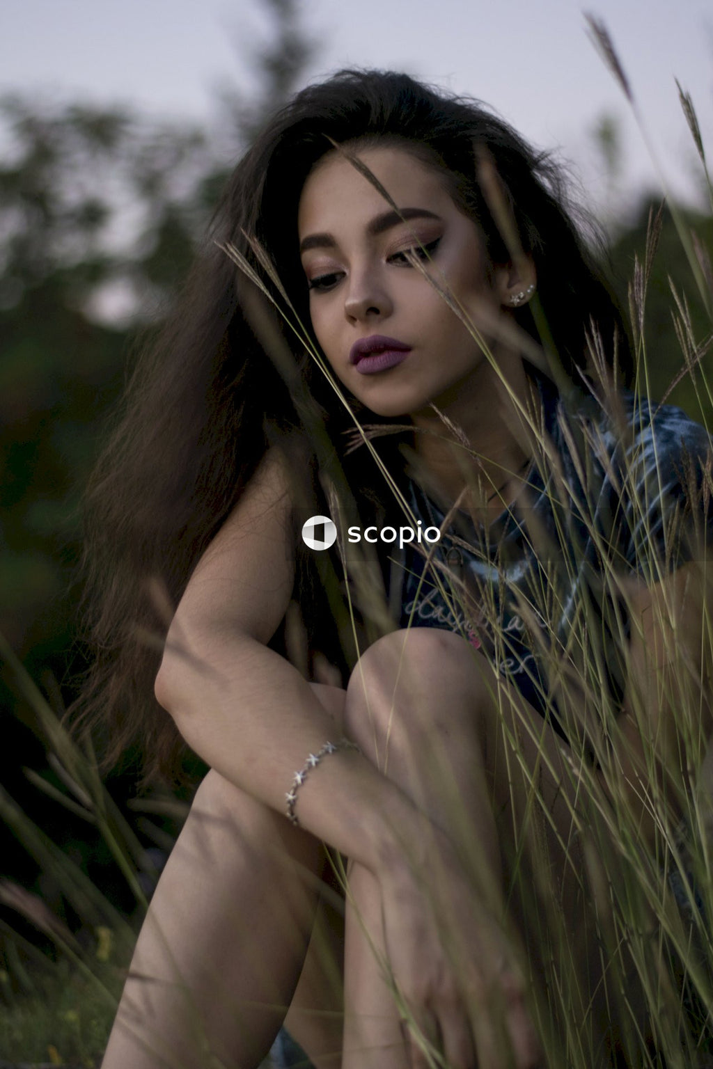 Portrait of woman with curly hair sitting on grass outdoor