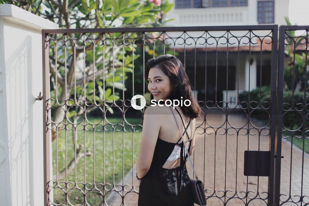 Woman in dark dress standing near dark dark metal gate