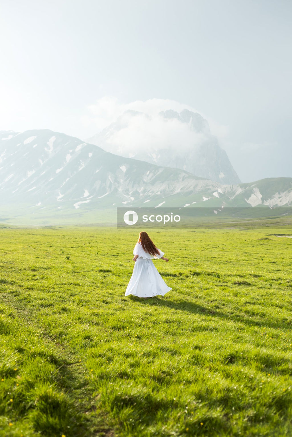 Woman in light dress standing on green grass field