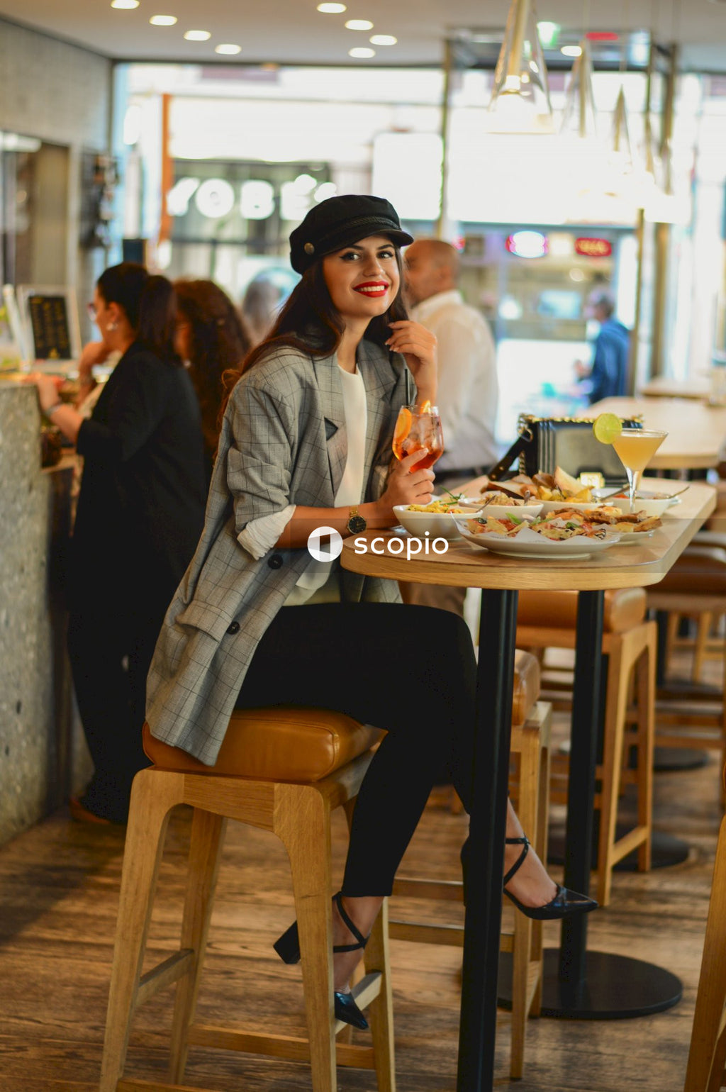 Woman smiling and sitting at a table with plates of food and drink