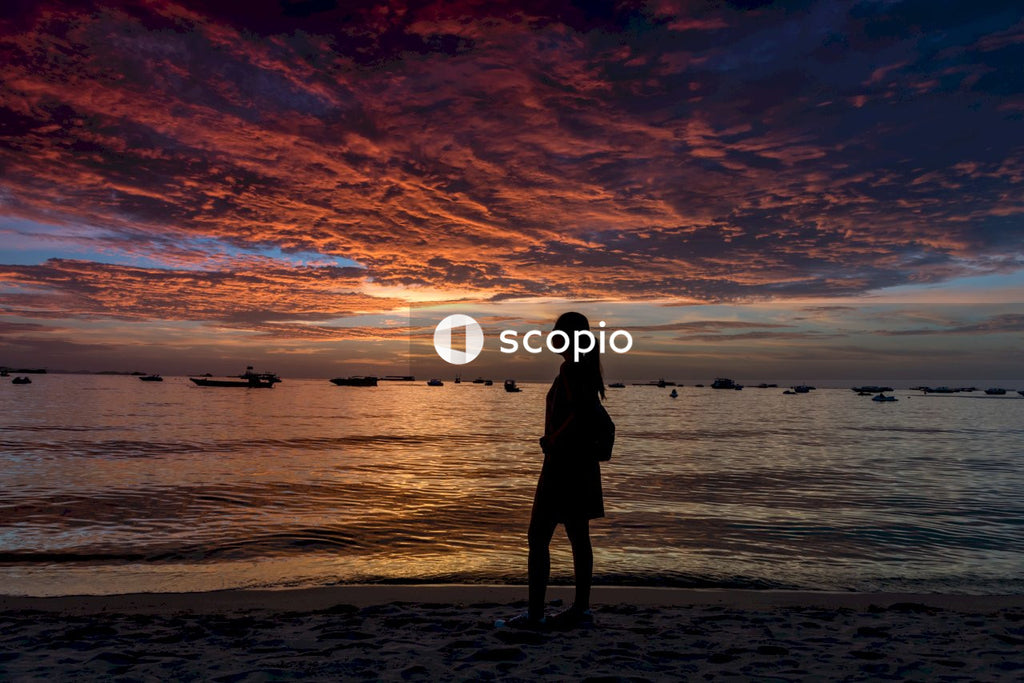 Woman in black dress standing on beach during sunset