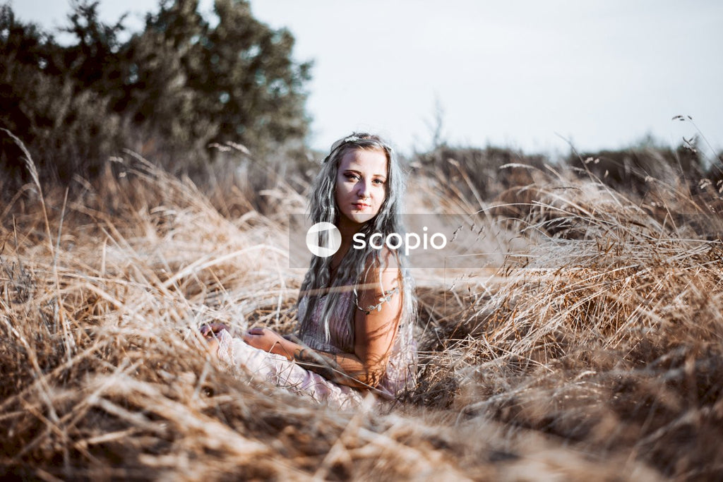 Woman in brown long sleeve shirt sitting on brown grass field