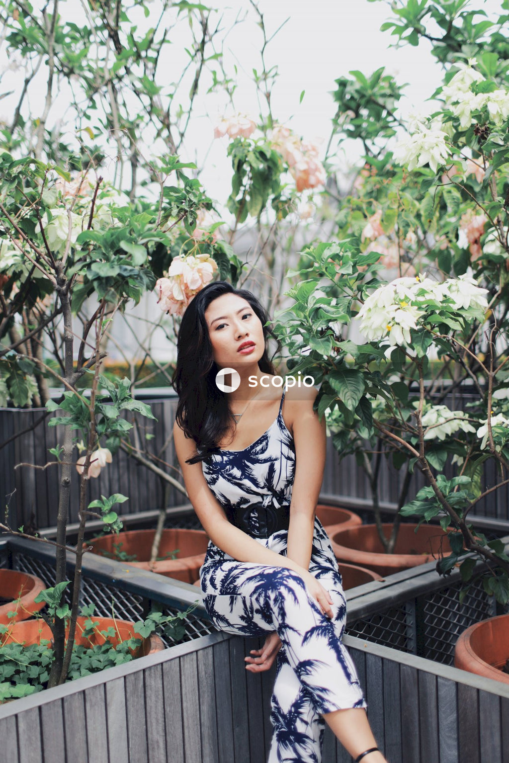 Woman wearing jumpsuit near flower bushes
