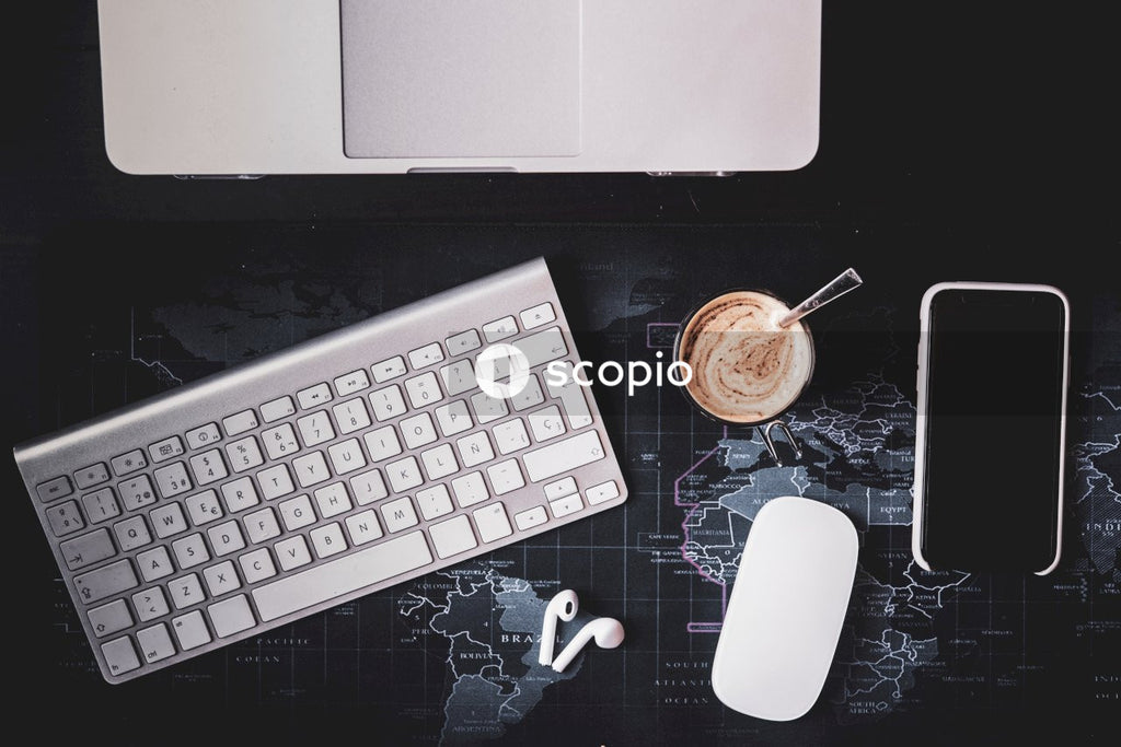Top view of coffee cup next to smartphone, laptop and earpods