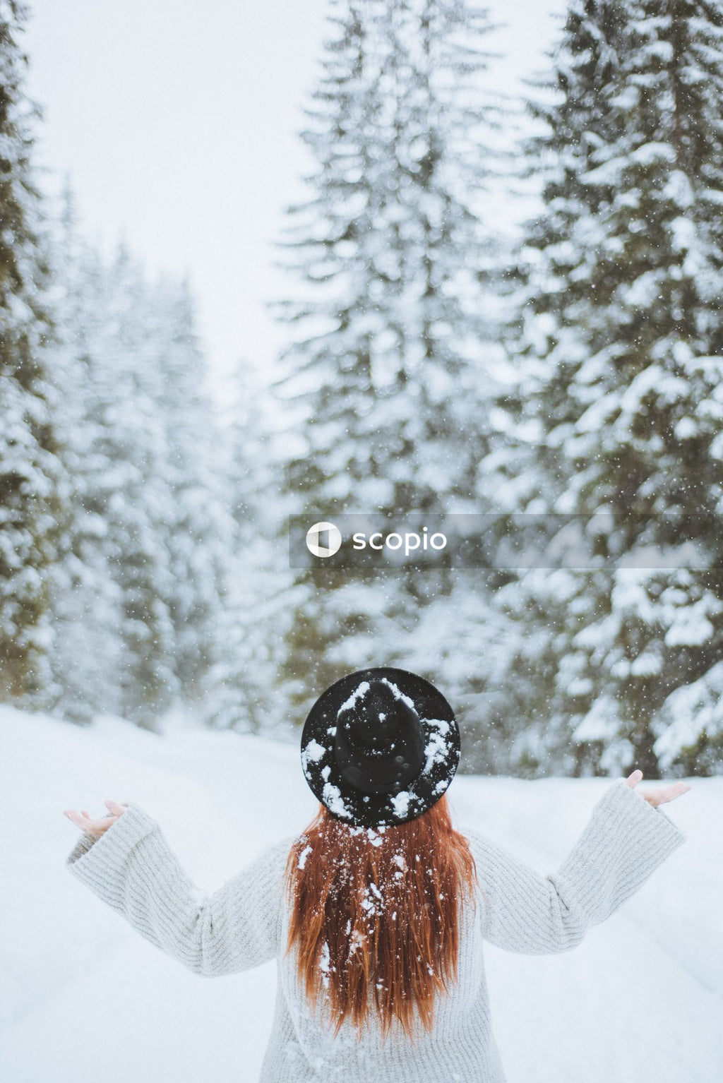 Person in orange jacket and black knit cap sitting on snow covered ground