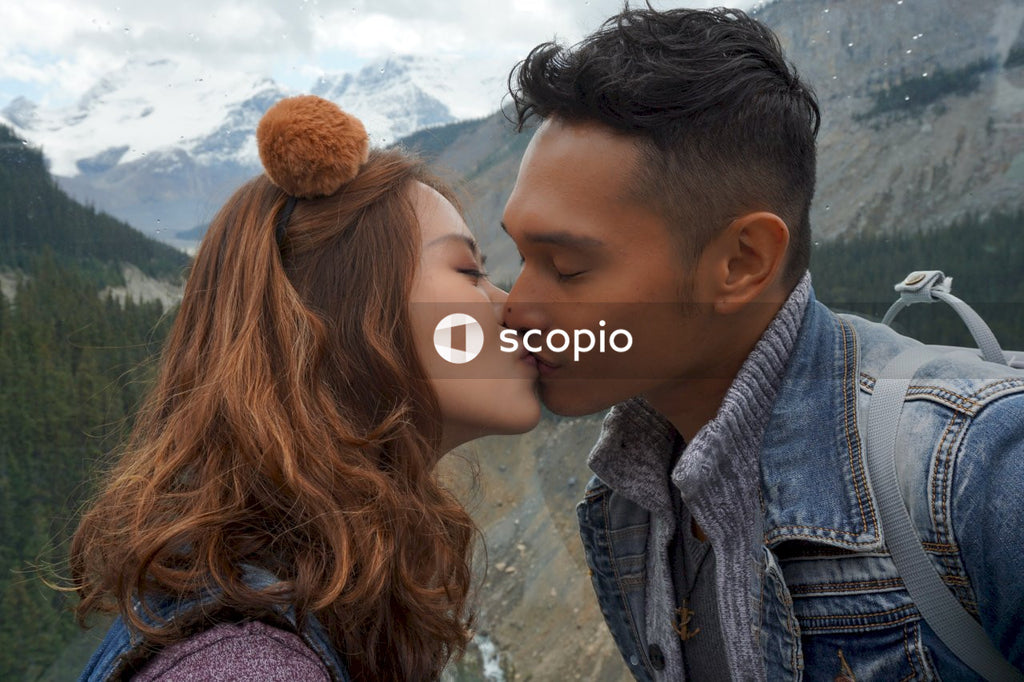 Man and woman kissing near mountains