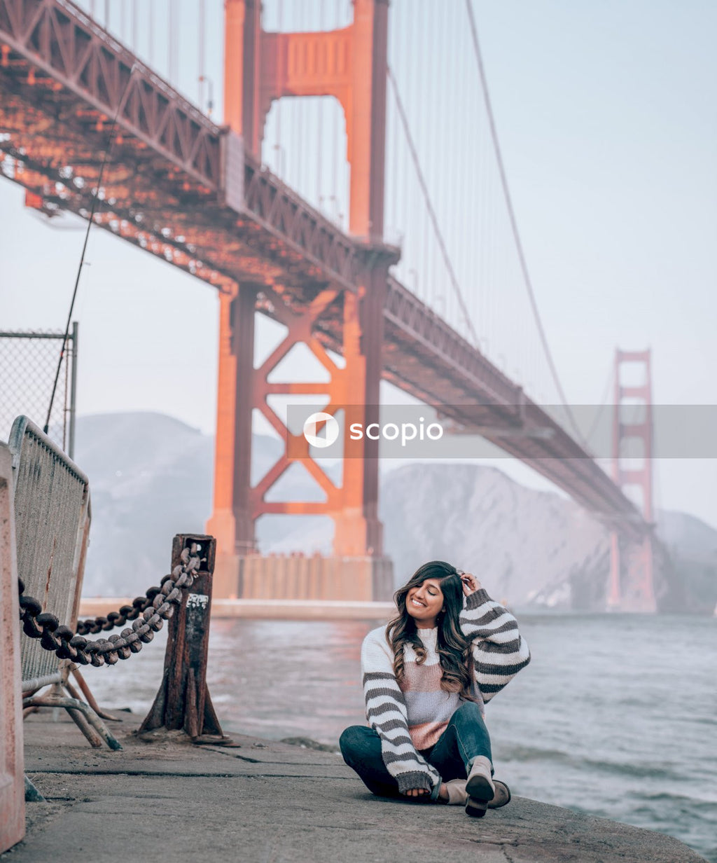 Woman in striped sweater sitting on floor near Golden Gate Bridge in San Francisco, California, United States