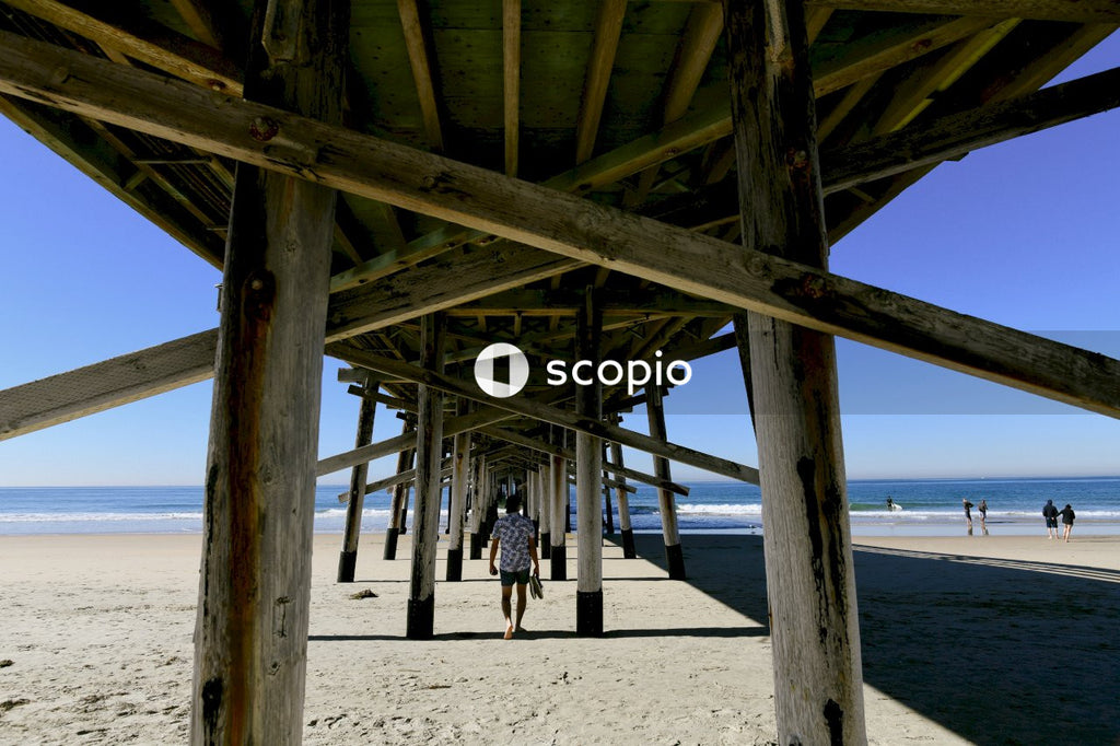People walking on beach under wooden dock