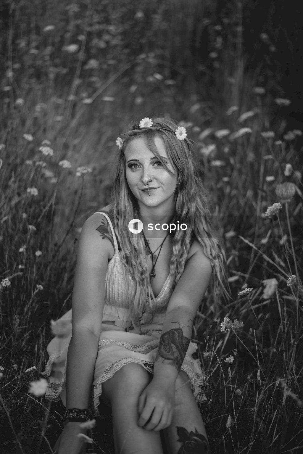 Grayscale photo of woman in tank top sitting on grass field