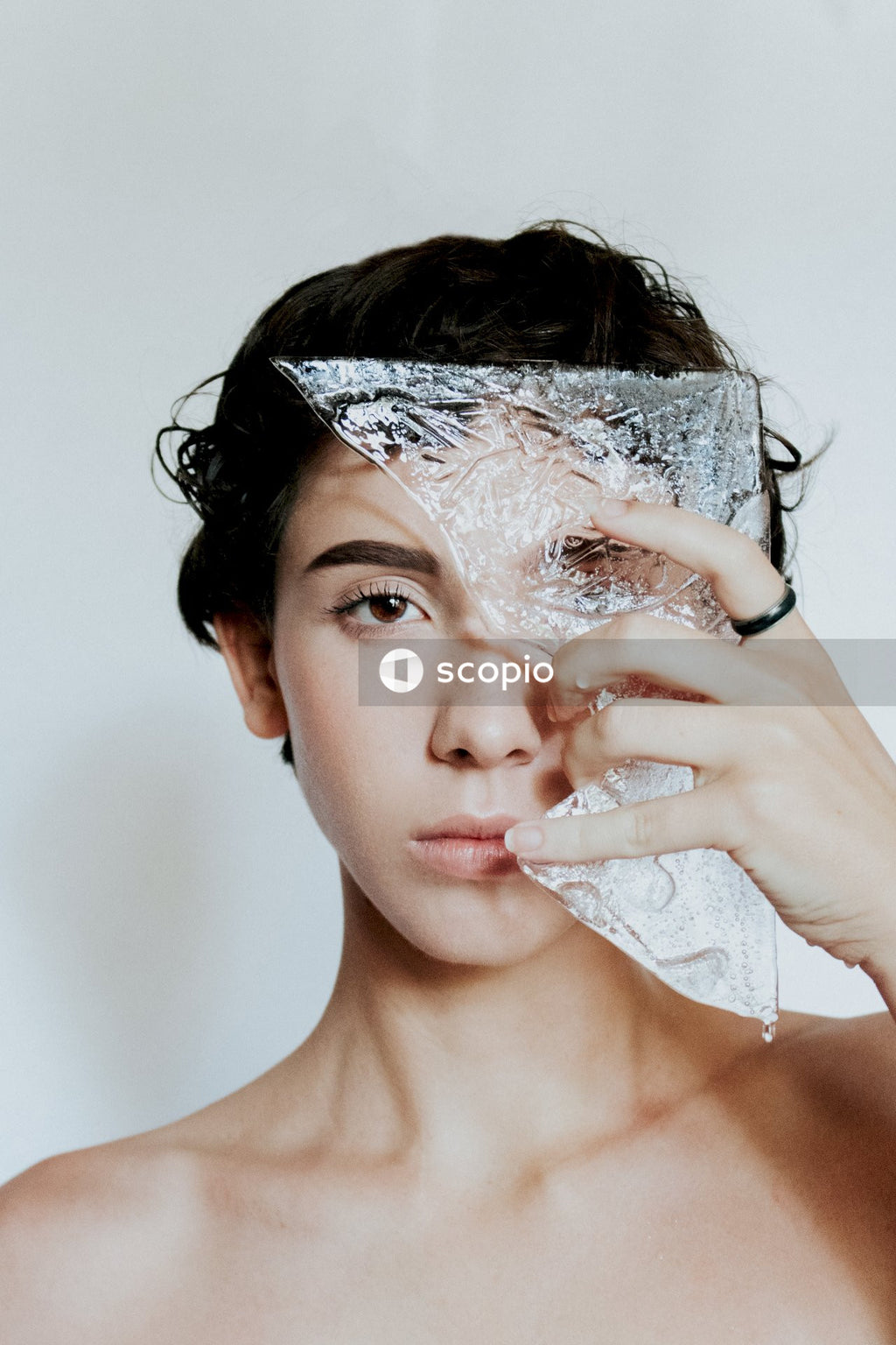Portrait of topless woman holding a broken glass next to her eye