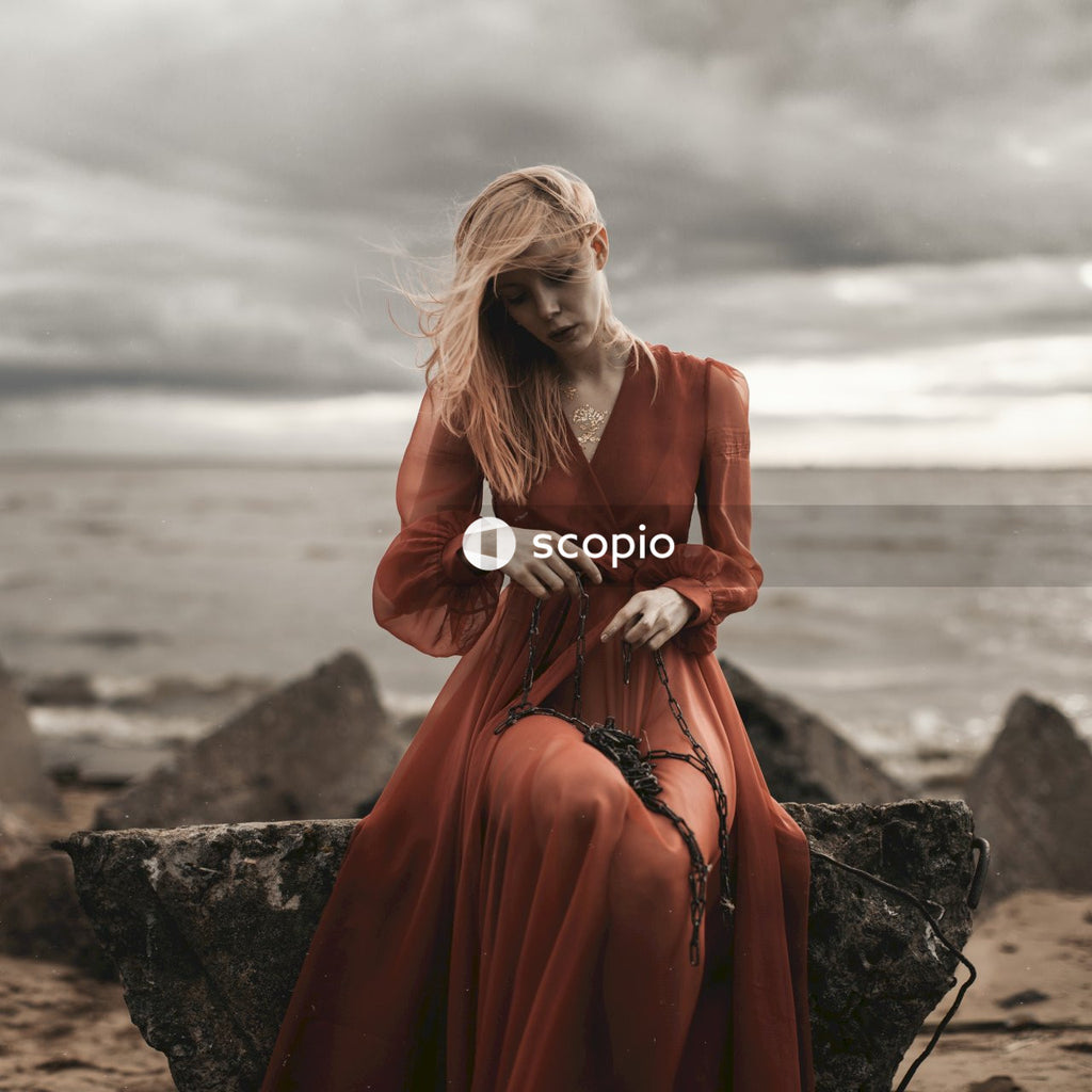 Woman wearing long sleeved red dress near the ocean