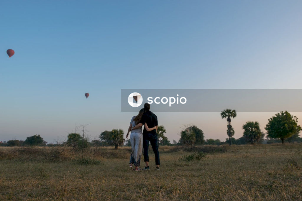 Woman and man hugging each other while watching three hot air balloons