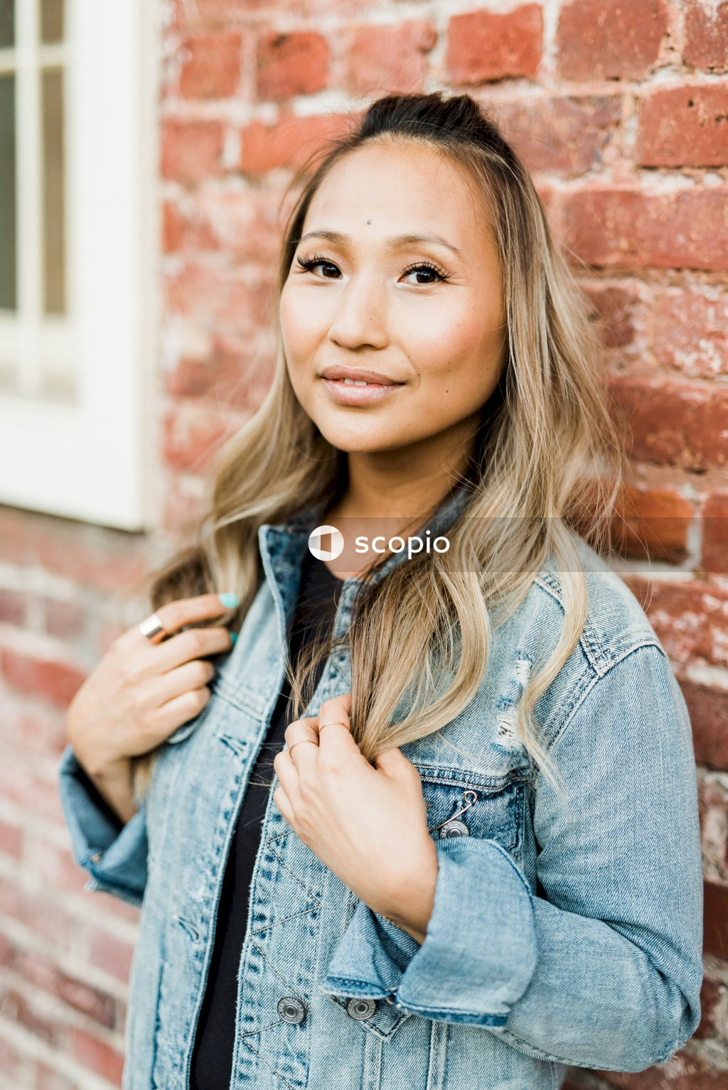 Woman in blue denim jacket leaning on a wall