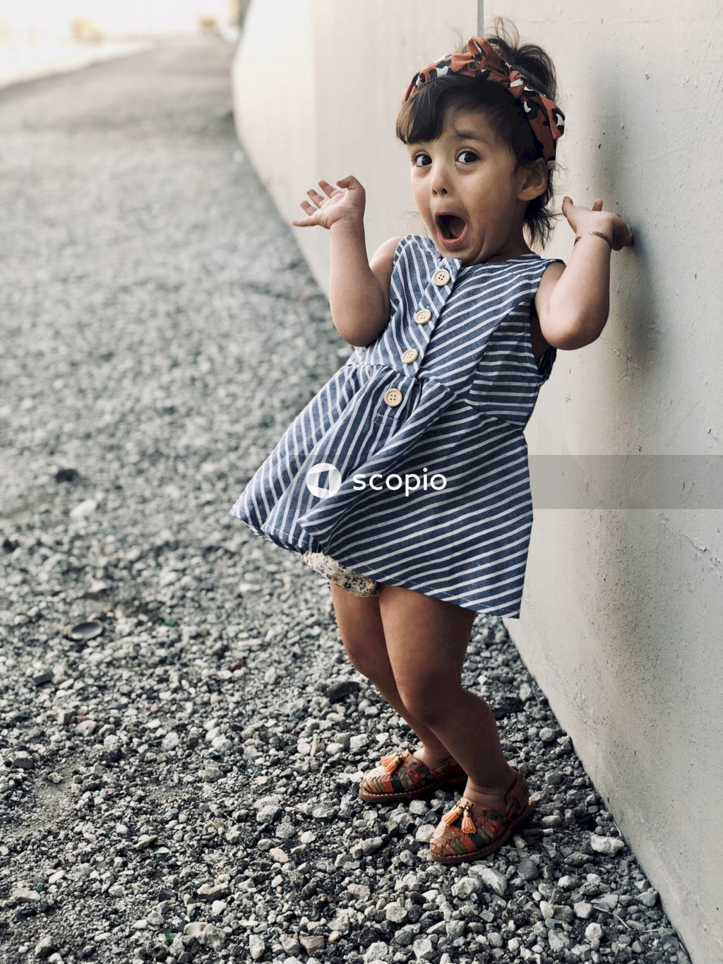 Young girl wearing dress in surprised gesture in front of wall