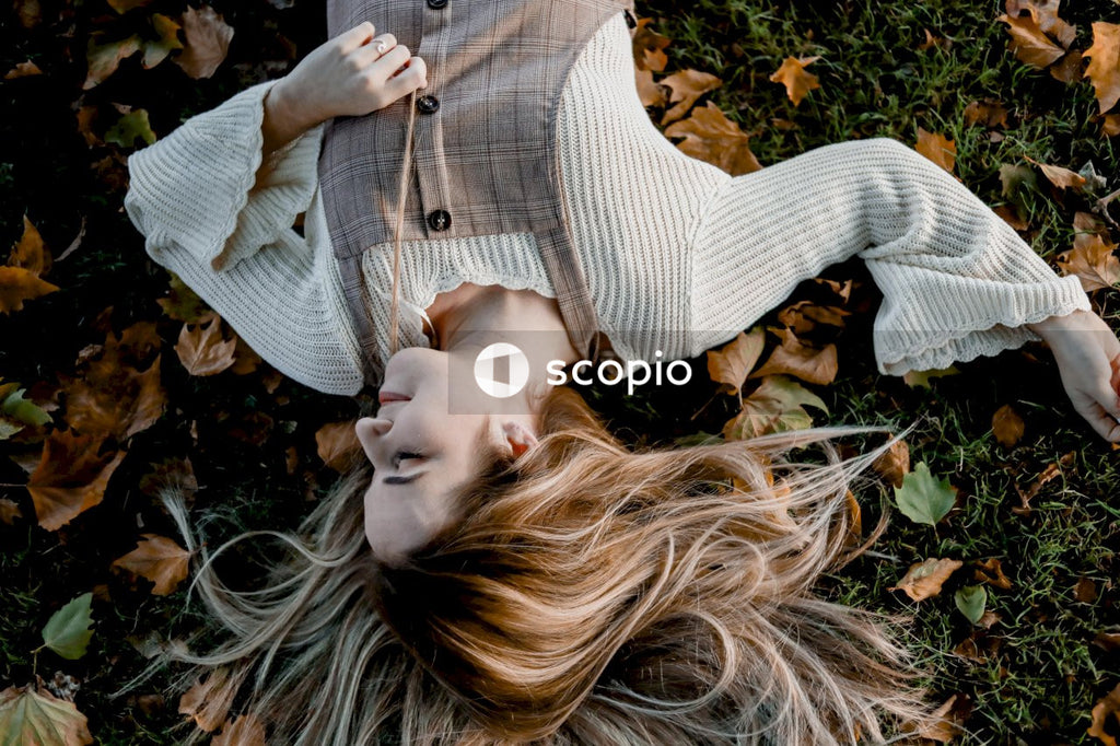Woman in gray sweater lying on green grass