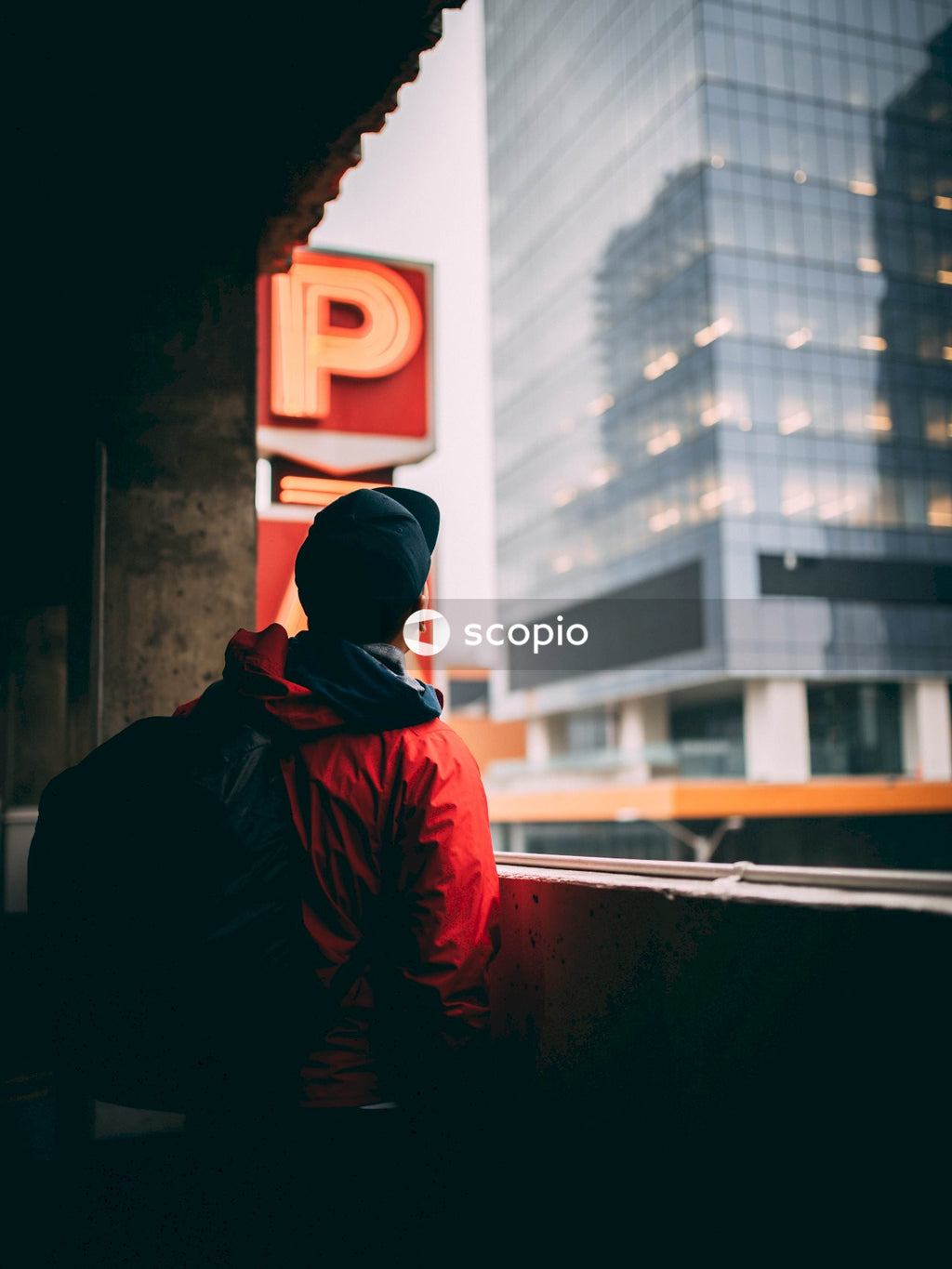Back view of man with backpack standing on balcony looking outdoor