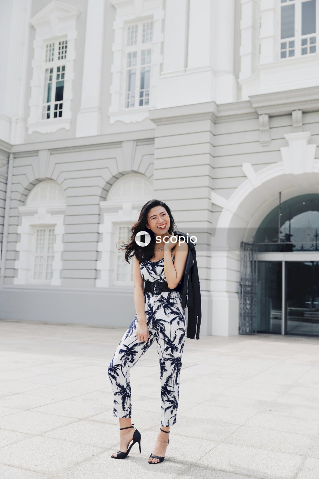 Woman in light and dark jumpsuit posing in front of building