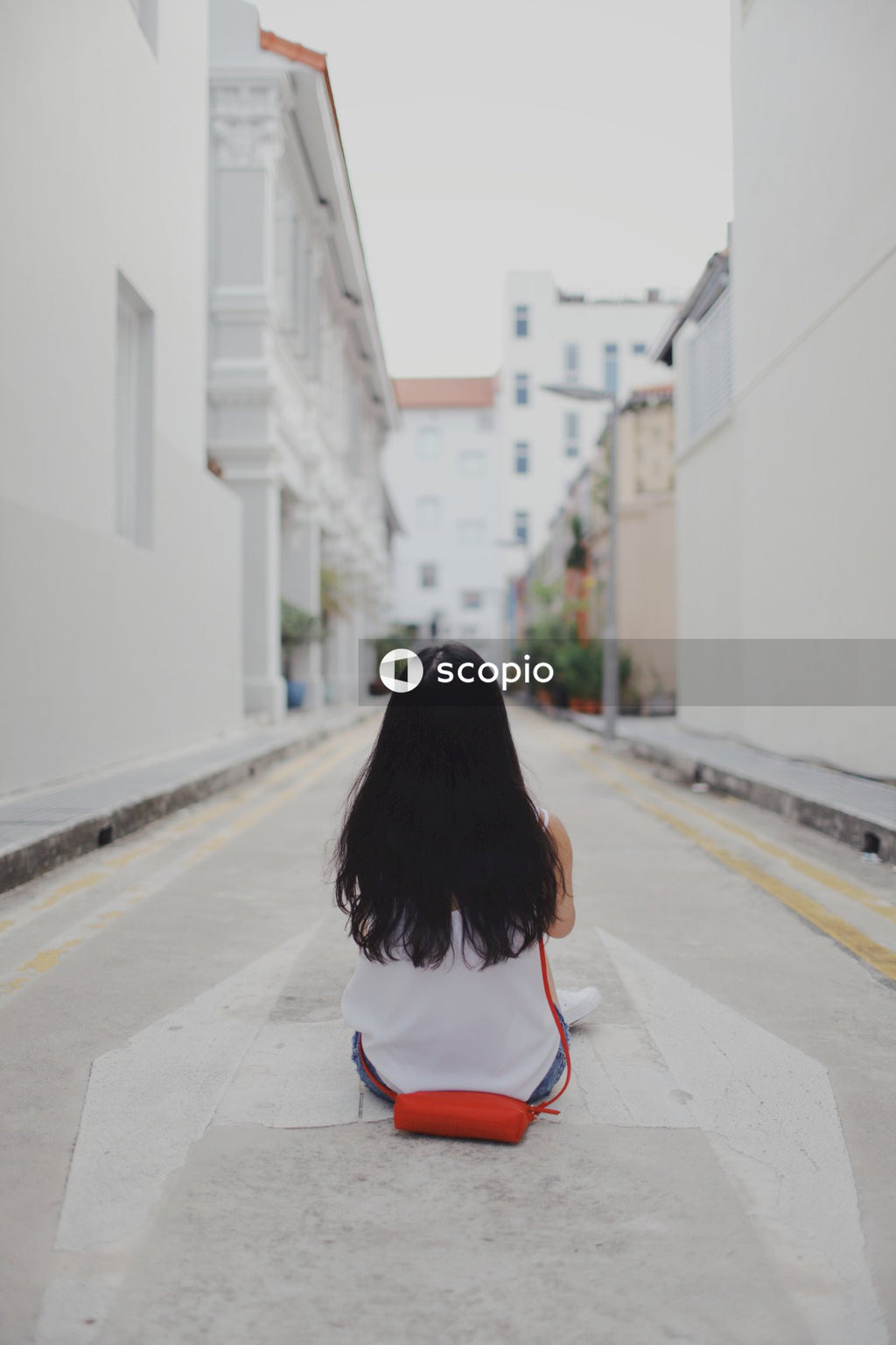 Backside of woman sitting on the street between buildings