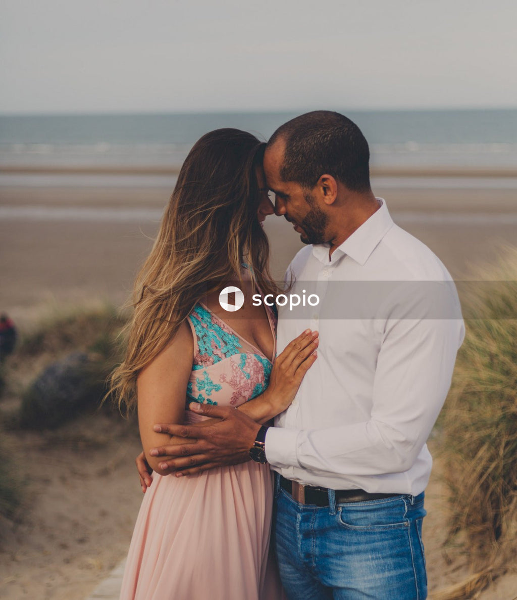 Man in white suit kissing woman in blue and white floral dress