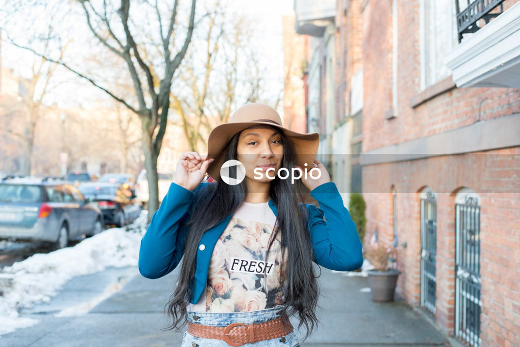 Woman wearing fedora hat standing on sidewalk