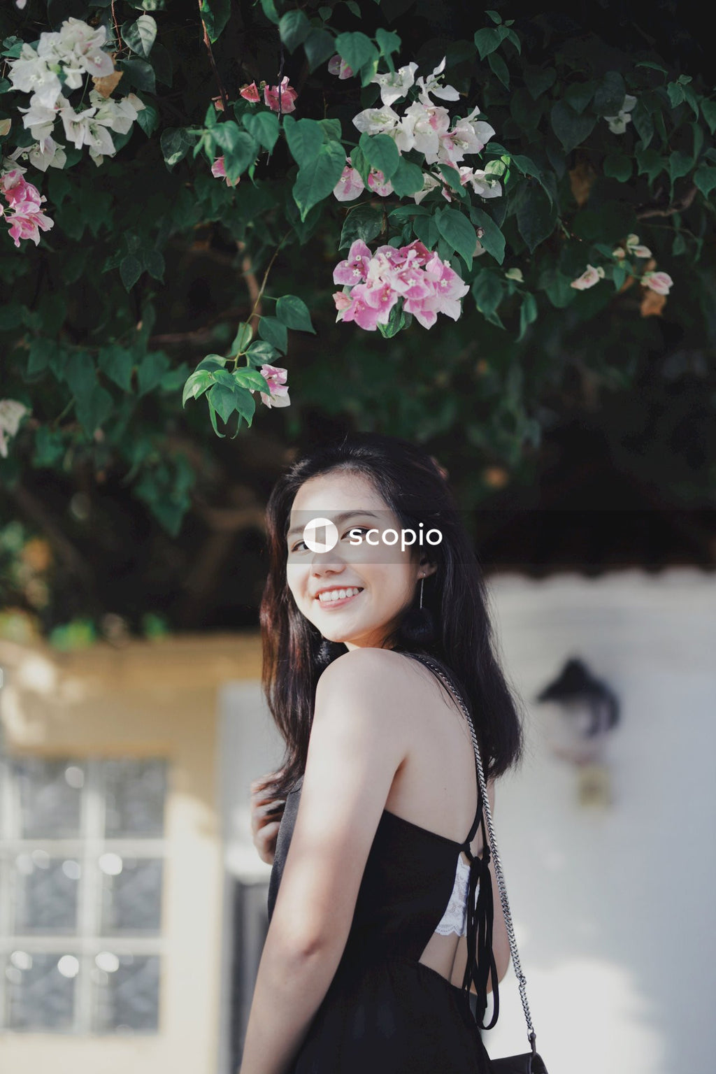 Woman in dark dress posing near flowers bushes