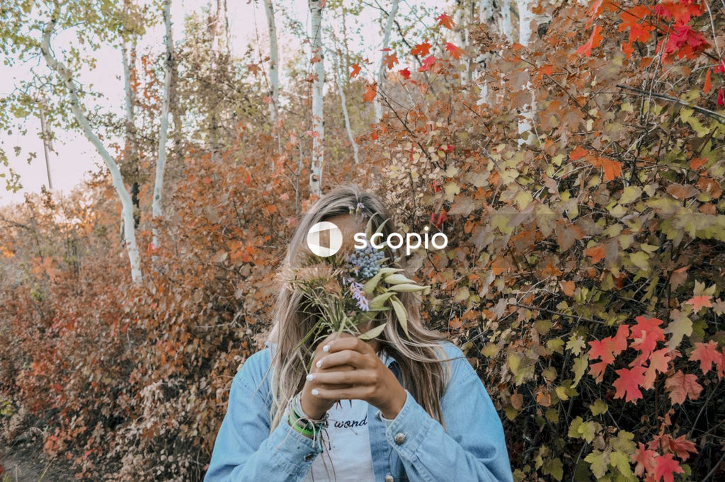 Woman in blue denim jacket standing near brown leaves tree