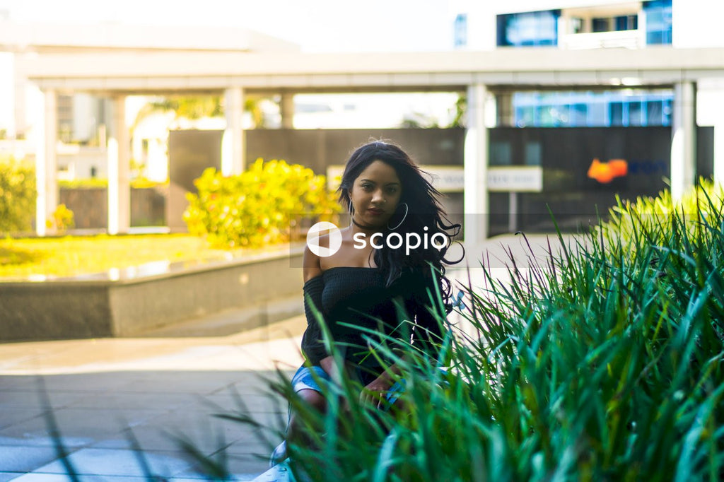 Woman in black tank top sitting on green grass field