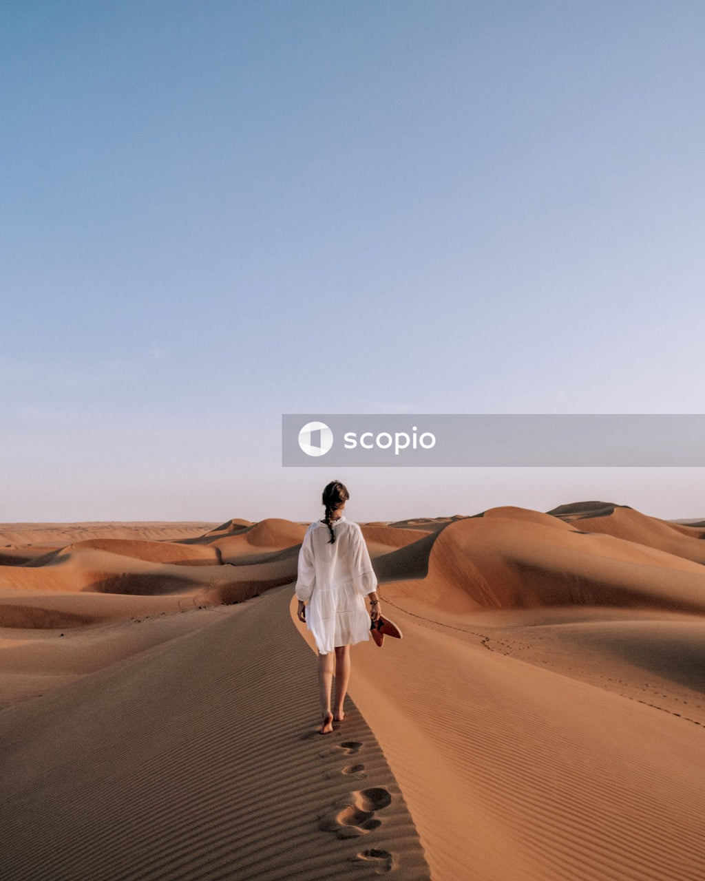 Woman in white dress walking on brown sand