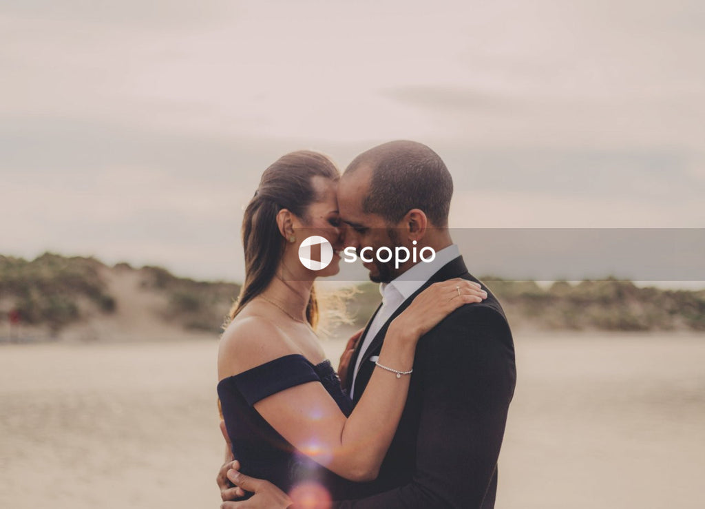 Man in black suit kissing woman in black spaghetti strap dress
